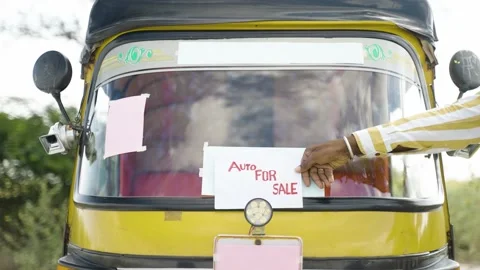 Cloe up shot of driver placing auto rikshaw for sale sign board in front of auto Stock Footage 168727416