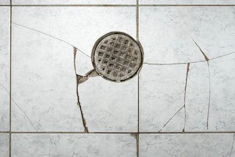 Clogged floor drain with broken ceramic tiles, obsolete bakdrop with cracks Stock Photos