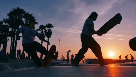 Clones skateboarding in Venice Beach skate park at sunset. Slow motion loop Stock Footage