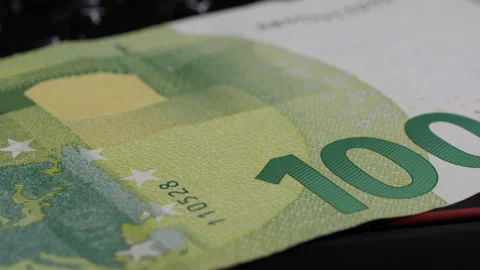 Close-up of 100 Euro banknote on black surface with keyboard in background Vídeos de archivo 344754500