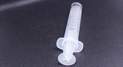 Close-up of a 10ml empty plastic syringe on a textured dark background, sym.. Stock Photos