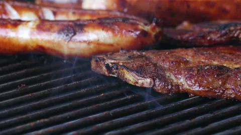 Close-up of 2 slices of meat and sausages on a grill. One slice of meat is being Stock Footage 163051492