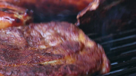 Close-up of 2 slices of meat on a grill. One slice of meat is being turned. Stock Footage 163051360