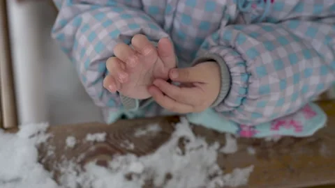 Close up of a 2 years old child playing with fresh snow Stock Footage 145730642