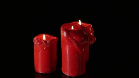Close up 3 lit red candles rotating around black background Video stock 75678983
