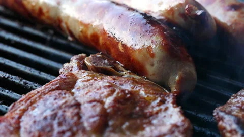 Close-up of 3 sausages and a slice of meat on a grill. The sausages are sizzling Stock Footage 163050979
