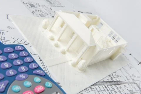Close-up of 3D model of the house printed on a 3D printer and calculator. Stock Photos
