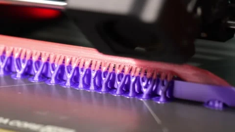 Close-up of a 3D printer extruding filament on a heated build plate with Stock-Footage 344301085