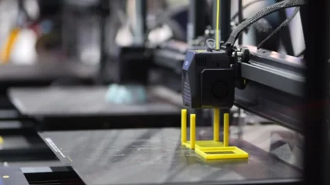 Close-up of 3D printer in motion, constructing yellow part Видео 345023715