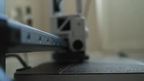 Close-up of 3D printer nozzle depositing filament onto build plate Видео 339182938