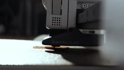 Close-up of a 3D printer nozzle depositing molten filament onto a build plate Видео 339201762