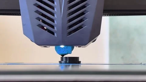 Close-up of a 3D printer nozzle extruding blue filament, building a small o.. Stock Footage 311646242