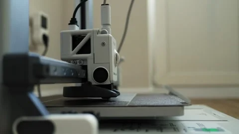 Close-up of a 3D printer nozzle moving across a build plate Видео 339182955