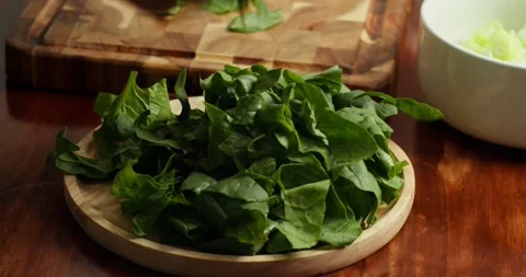 Close-up 4K: A chef arranges fresh spinach on a wooden cutting board on a wooden Stock Footage 317719709