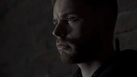 Close-up in 4K of a handsome young man standing against a wall looking away with Stock Footage 107527831