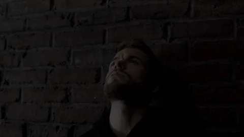 Close-up in 4K of a handsome young man leaning against a wall raising his head 動画素材 107528358
