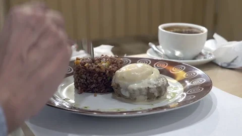 Close-up. 4k. the man eats red rice with beef steak and egg poached, with Видео 83234439