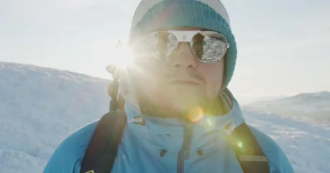 Close 4k portrait of young smiling male hiker wearing sunglasses in mountains Stock Footage 133888641