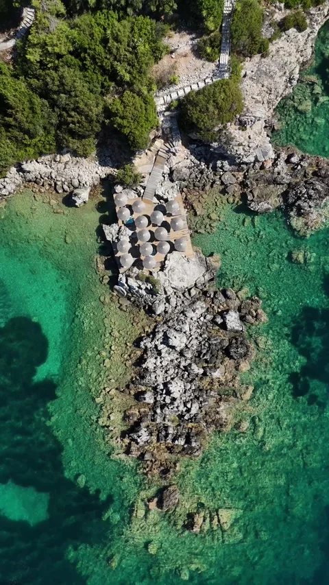 Close up 4K vertical drone shot of rocky reef islet in crystal clear turquoise s Stock Footage 340560500