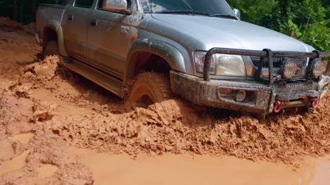 Close up of 4x4 SUV tire spinning in deep mud with heavy splash. Cinematic .. Stock Footage 337805203