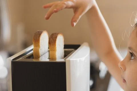 Close-up of a 5-7 year old girl who is preparing breakfast from toast in a Stock Photos