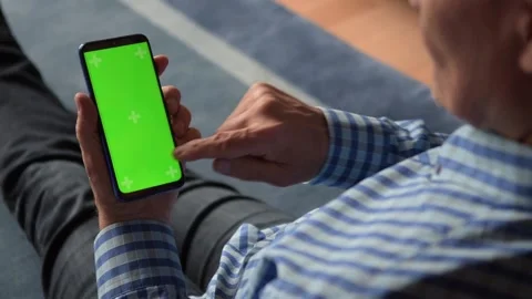 Close-up of a 66-year-old man using a smartphone with a green Chroma Key screen, Stockbeeldmateriaal 156640968