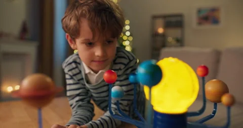 Close-up of 7-year-old boy looking at child's model of the solar system. He is 库存影片 210494386