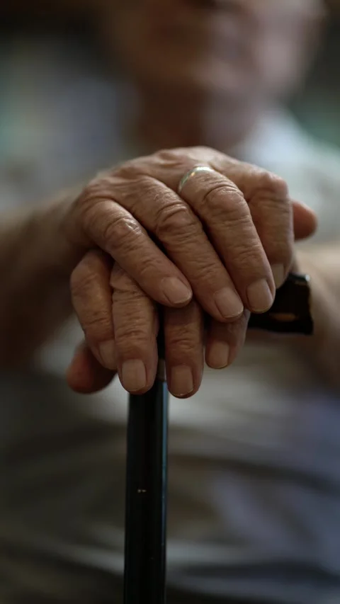 Close-up of 80-year-old man's wrinkled hands resting on a black cane Stock Footage 346175756