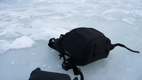 Close-up of an abandoned backpack on thin frozen sea ice, suggesting a lost Stock Footage 332045815