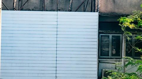 Close-up of abandoned building facade with dark grid windows, peeling paint.. Stock Photos