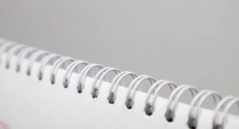 A close-up, abstract shot of the white plastic spiral binding of a notebook.. Stock Photos