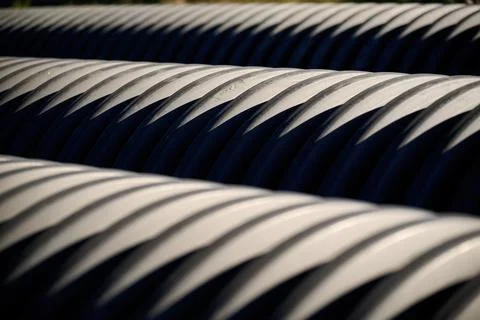 Close up abstract view of stacked large black corrugated plastic pipes showin Stock Photos