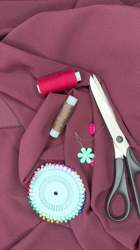 Close-up of accessories for cutting and sewing a burgundy silk dress Stock Footage 306561094