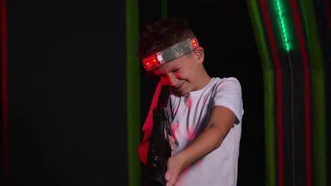 Close-up of an active boy holding a laser weapon and aiming, a laser tag game. Stock Footage 321814218
