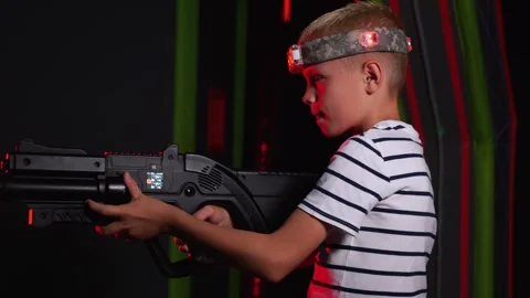 Close-up of an active boy holding a laser weapon and aiming, a laser tag game. Stock Footage 322215436