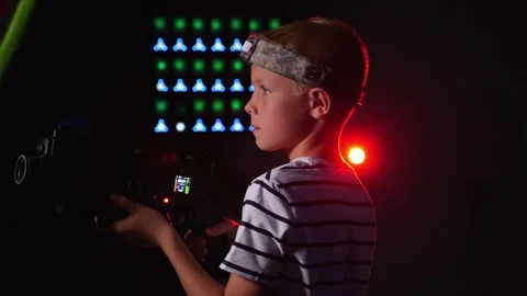 Close-up of an active boy holding a laser weapon and aiming, a laser tag game. Stock Footage 322215536