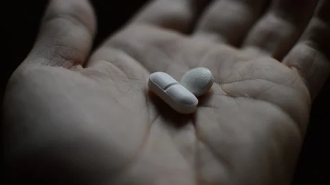 Close-up addicted man's hand with opioid pills on a dark background. 库存影片 225858292