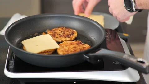 Close-up of adding cheese to chicken burgers while frying on a hotplate. Stock Footage 141070401