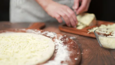 Close-up adding cheese on top of the pizza in slow-motion in 4K. Stock Footage 137484614