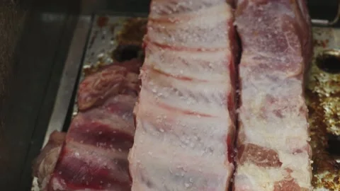 Close-up adding grill salt to two pieces of pork ribs during the day in 4k Stock Footage 170020593