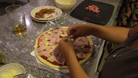 Close-up adding pieces of ham on a homemade pizza preparing in the kitchen Stock Footage 193086297