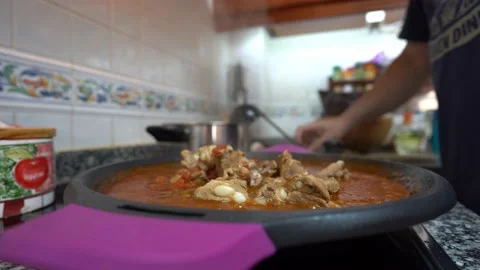 Close up adding the pork to mix it with the rest ingredients of a paella Stock Footage 163925944