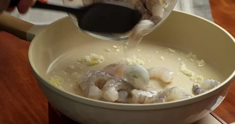 Close up of adding raw shrimp into a hot pan with garlic and oil. seafood Vidéo 333325435