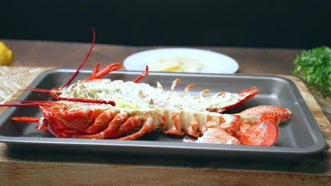 Close-up of adding sliced parmesan cheese on a cooked lobster before grilling. Video stock 146343852