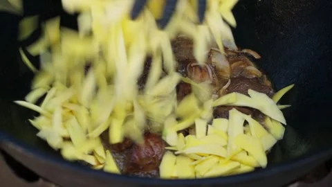 Close-up adding sliced yellow carrots to large kazan for pilaf Stock Footage 346539681
