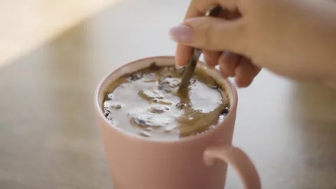 Close up of adding sugar and stirring cold iced coffee with spoon Stock Footage 342240546