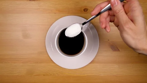 Close up adding sugar to a coffee cup, stirring and picking up cup in 4k. Stock Footage 86537512