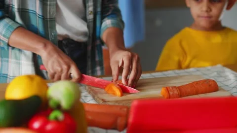 Close-up of adorable youngboy watching how his mother cutting vegetables for Stock Footage 147270921
