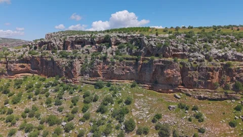 Close Aerial Approach to Ancient Cliff Caves and Rugged Rock Formations Stock Footage 340987537