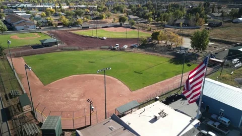 Close up aerial of baseball diamond and USA flag in neighborhood in Williams AZ Stock Footage 254121925
